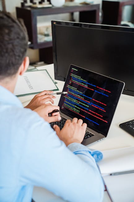 A person seated at a desk engaged in gardening website research, with a laptop displaying colorful coding or website analytics, and a gardening-related booklet or folder labeled 'GARDENING'. In the ba
